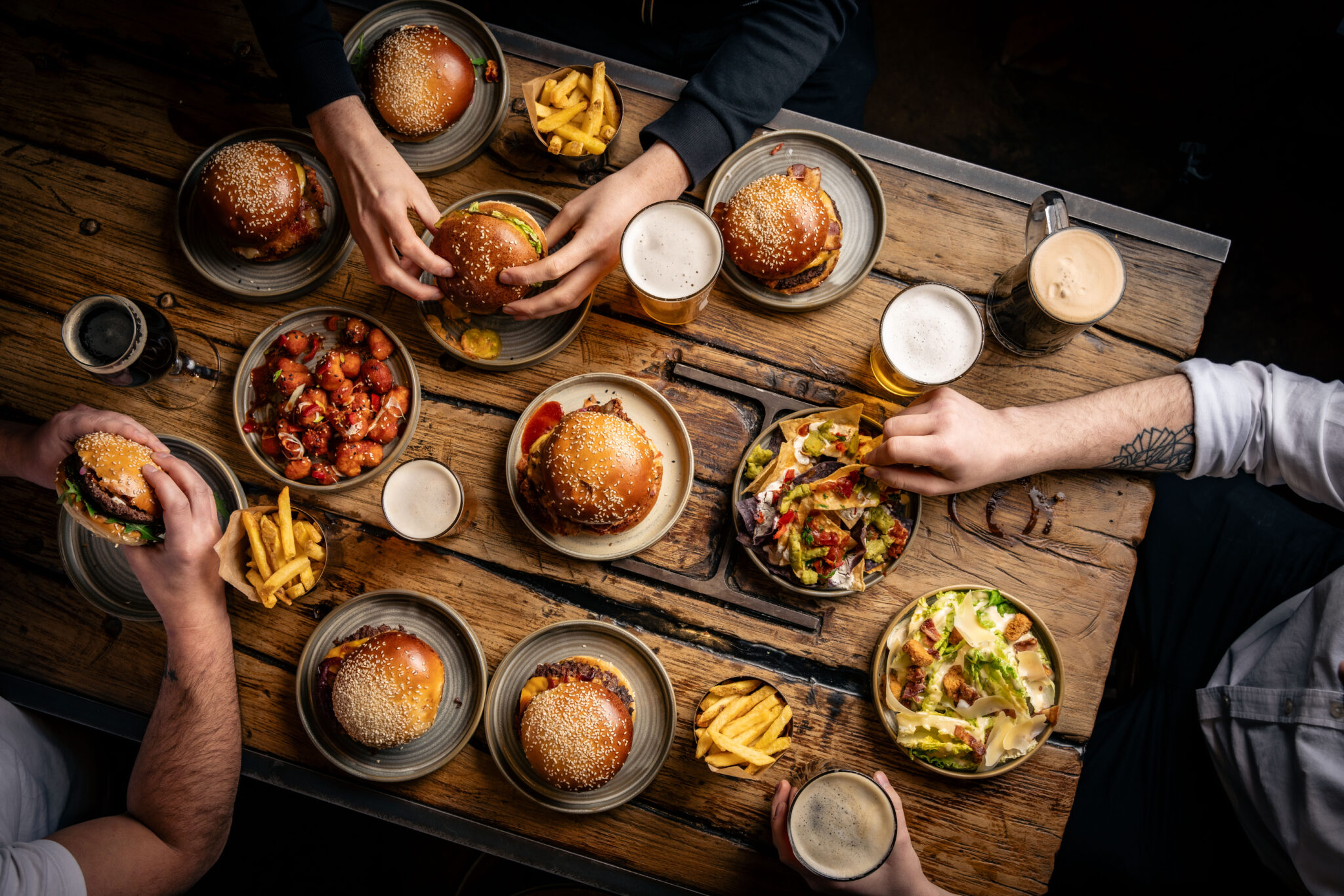 A group of people eating burgers and drinking craft beers